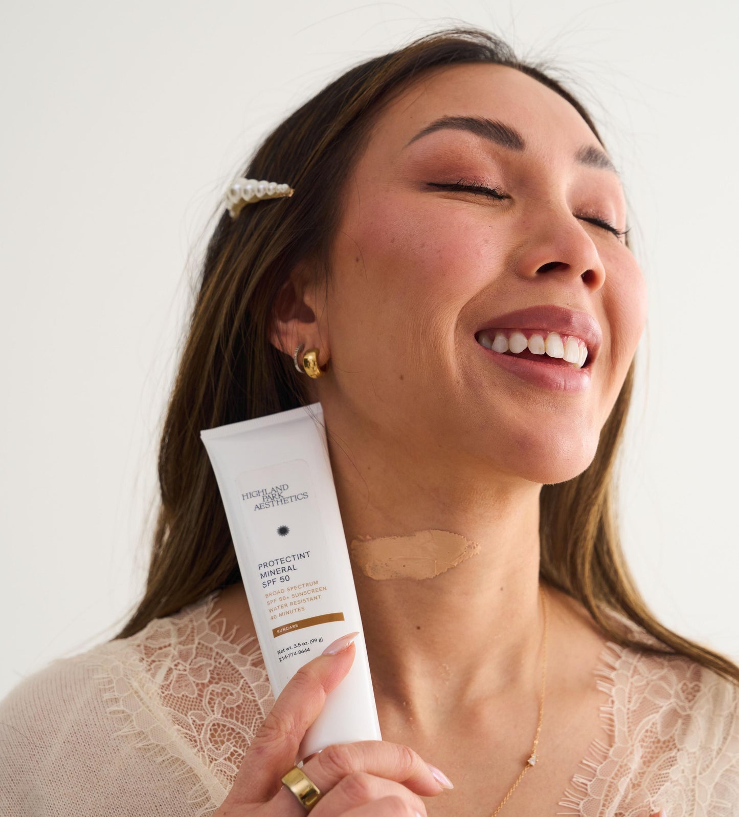 Woman holding a skincare product against a white background
