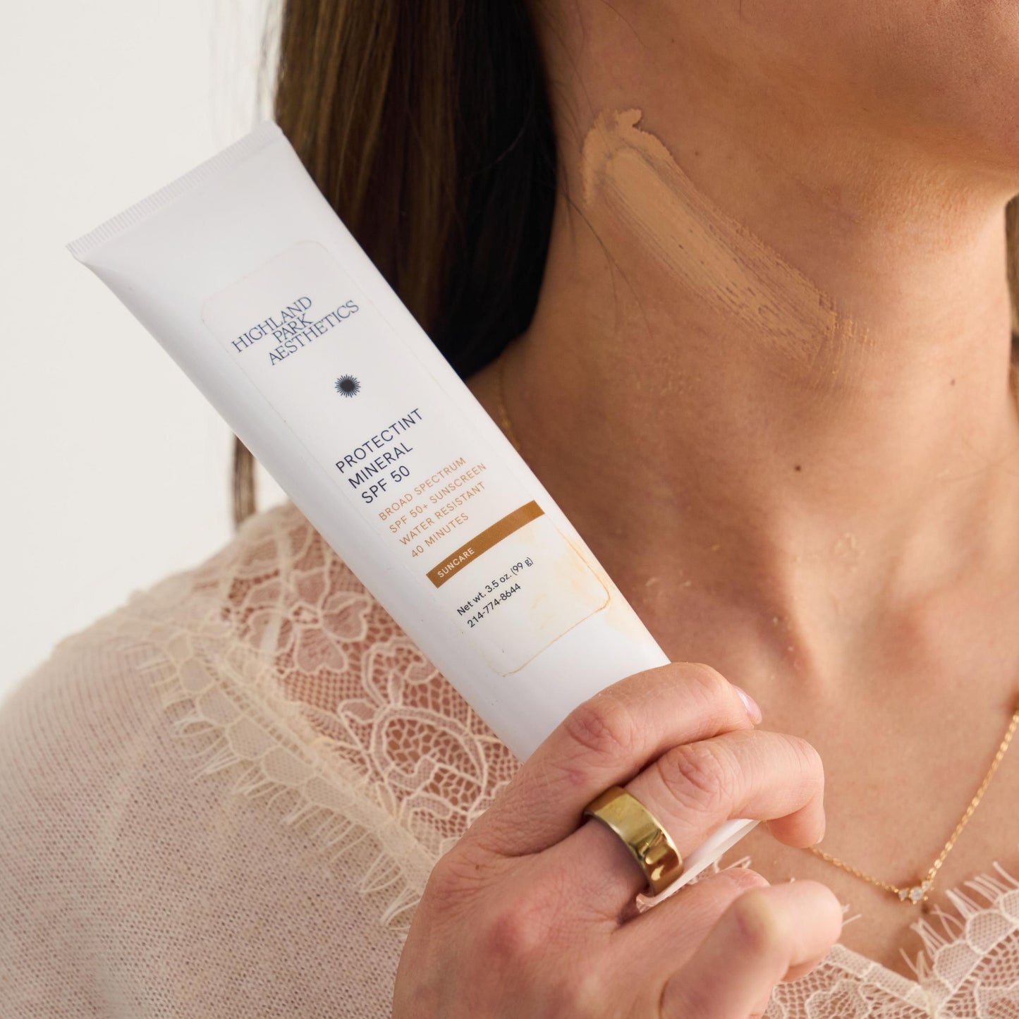 Woman holding a skincare product with a plain background